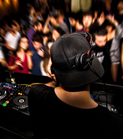 DJ with headphone and dj set at night club party. People at the